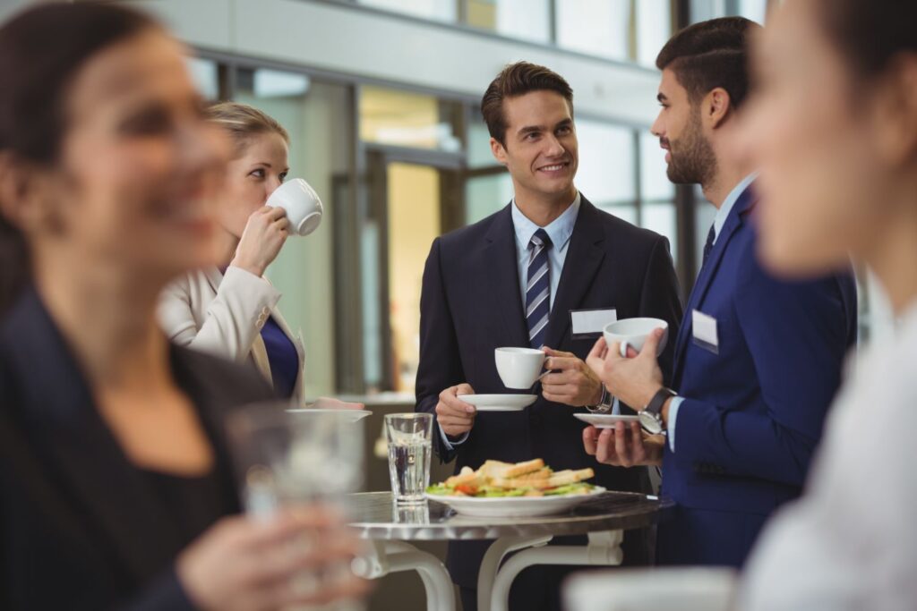 Personen in Businesskleidung, die Kaffee trinken und sich unterhalten