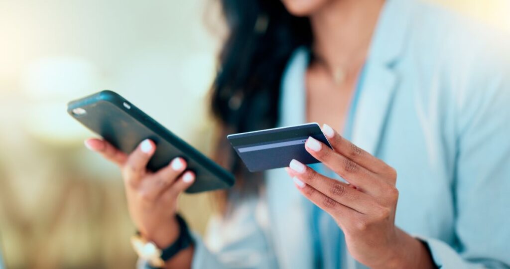 Frau hält Handy und Kreditkarte in den Händen. 