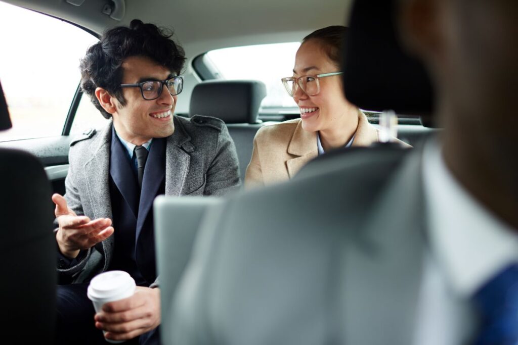 Eine Mann und eine Frau sitzen auf der Rückbank eines Taxis und unterhalten sich. 