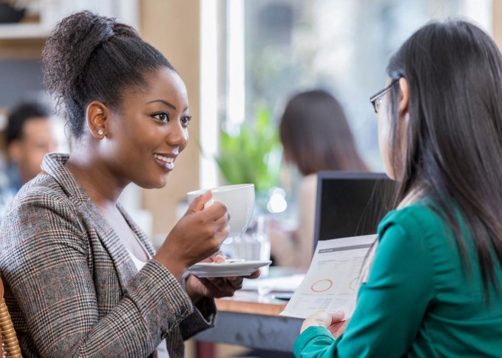 Two women discussing business over coffee.