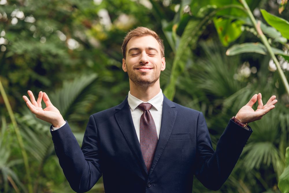 Nachhaltige Geschäftsreisen Mann im Anzug steht lächelnd und meditierend im Dschungel