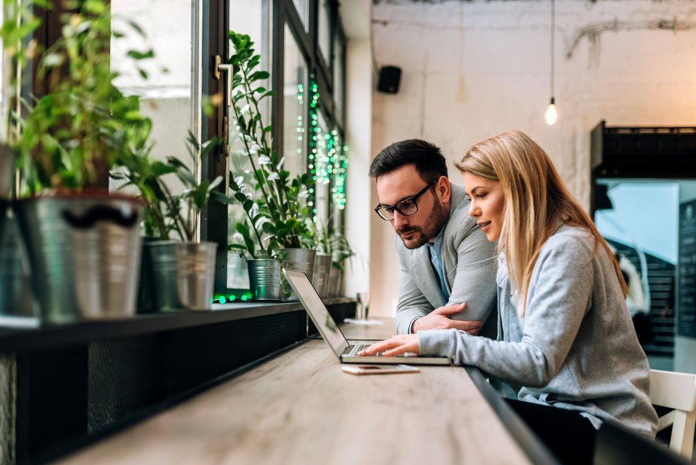 Mitarbeiter:innen sitzen am Café und arbeiten an der Reiserichtlinie