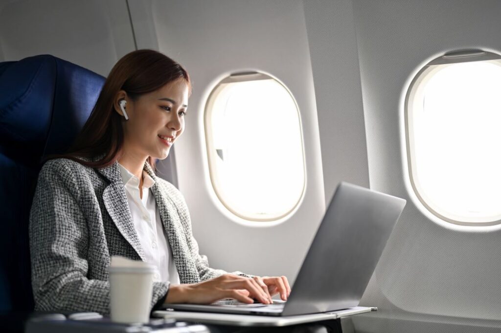 Frau arbeitet während des Fluges an Ihrem Laptop