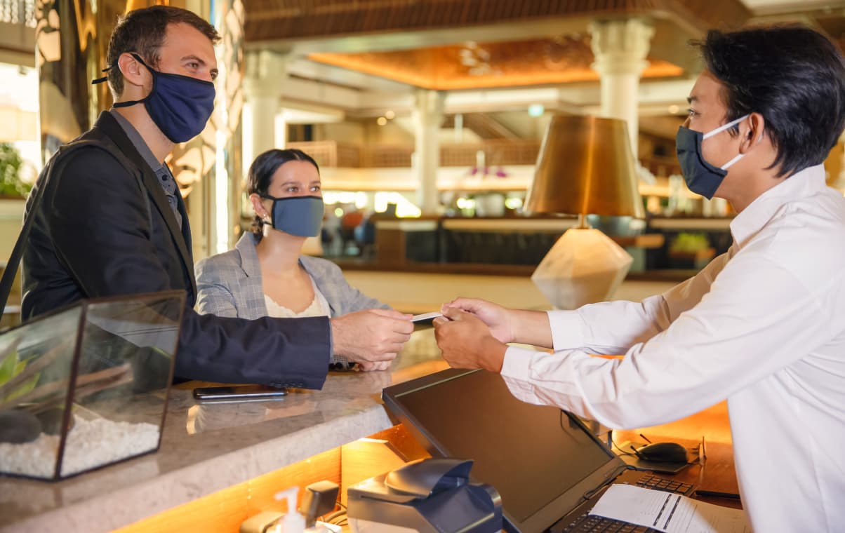 couple checking in a hotel with their face masks on